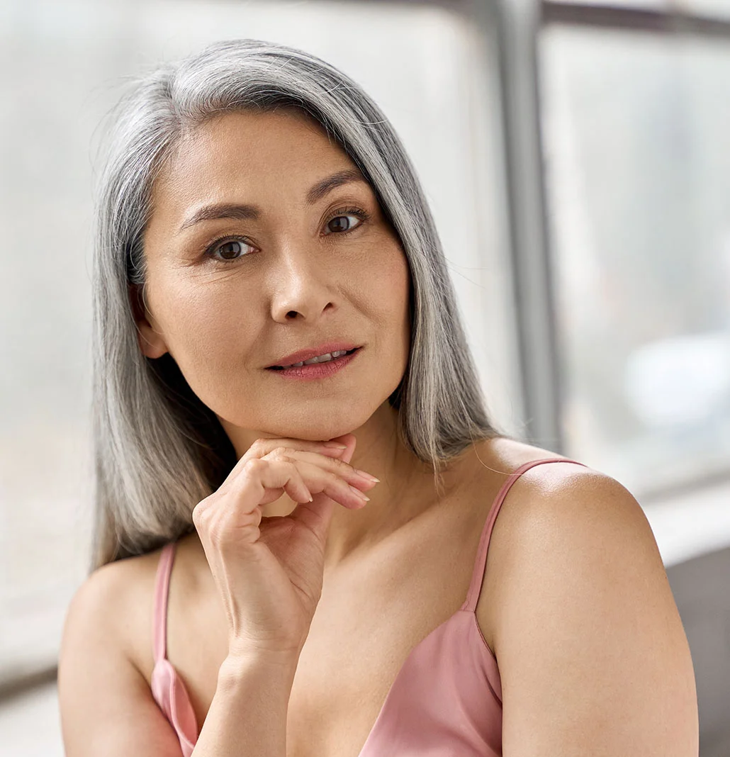 Middle aged asian woman with her hand to her chin | Blepharoplasty | NYC