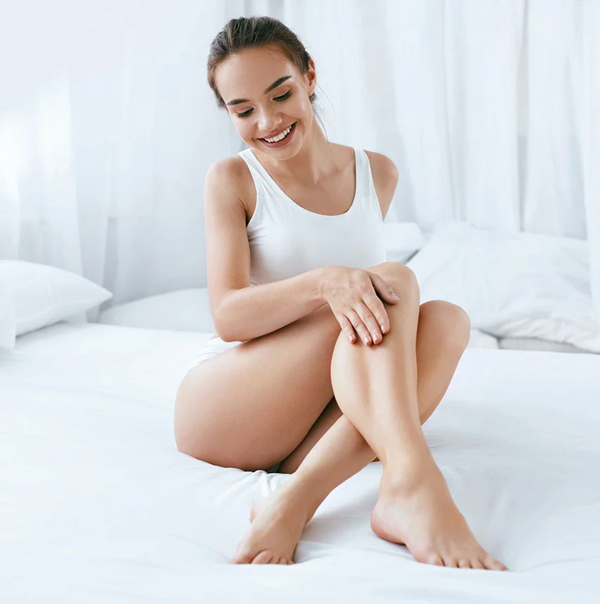 Woman on bed wearing white shirt showing her legs | Vein removal | NYC