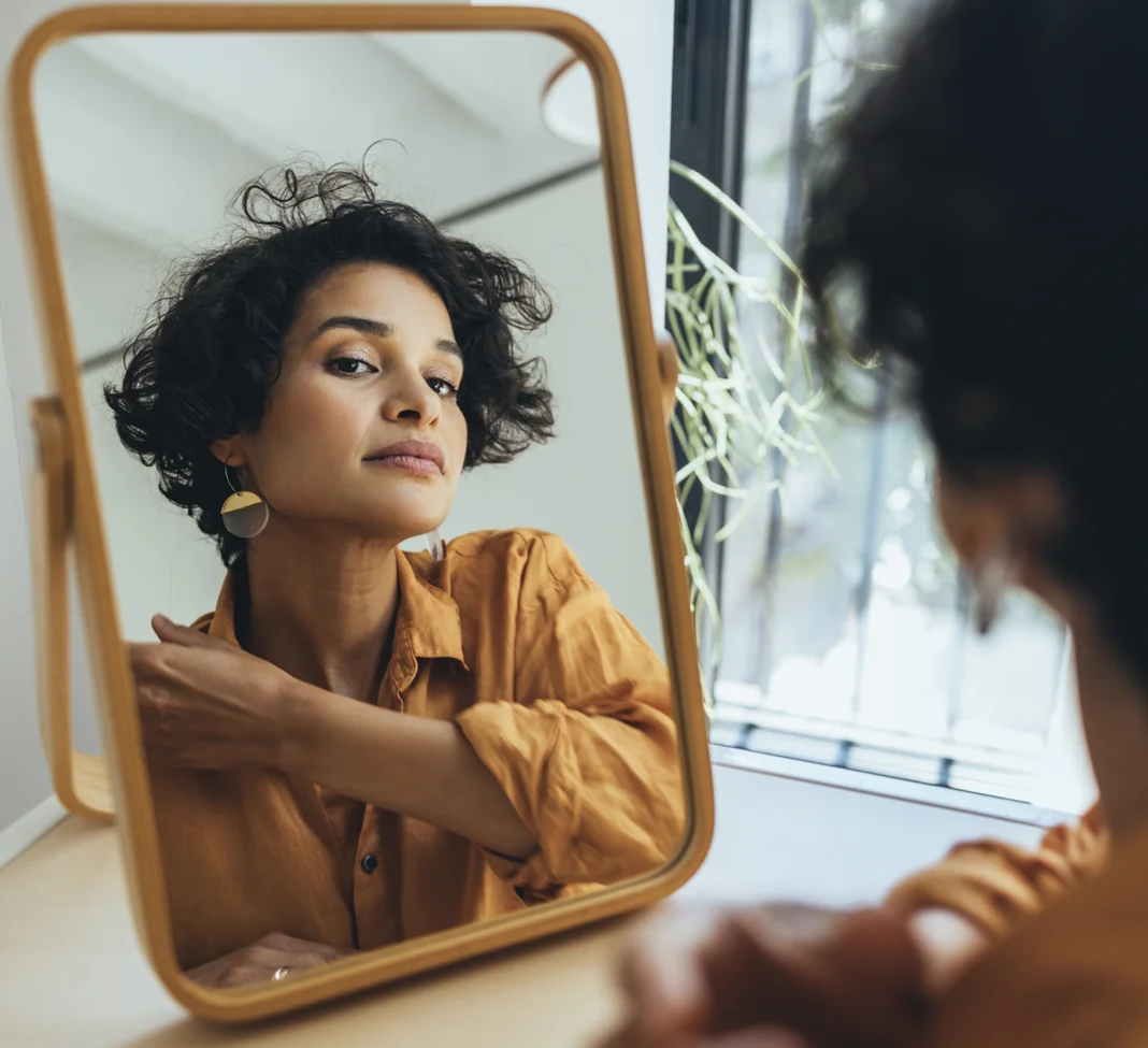 Middle aged woman looking at her face in a mirror | Lip Lift | NYC